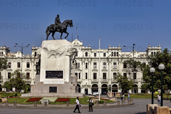 Equestrian statue on a large pedestal in front of an imposing historic building under a blue sky, Downtown Lima in Peru