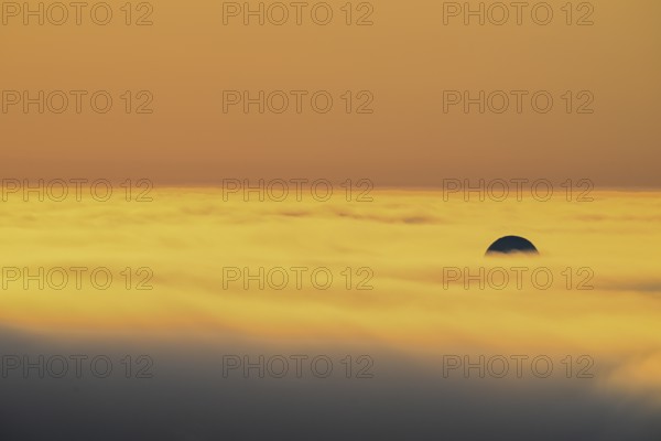 View from Mount Domen. Thick sea fog hangs over the Barents Sea and the midnight sun shines in an orange sky in the north. A dome of the NATO radar station in Vardö rises through the fog., Domen, Vardö, Finnmark, Norway