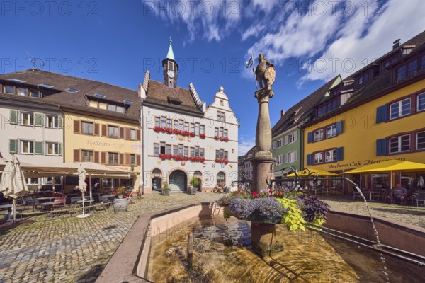 Market fountain, decoration with plants and flowers, historic town hall, outdoor area of a restaurant, café town hall café, Heitzmann bakery, cobblestone square, blue sky, cumulus clouds, intersection of main street with Kirchstraße, Staufen im Breisgau, Black Forest, Breisgau-Hochschwarzwald district, Baden-Württemberg, Germany