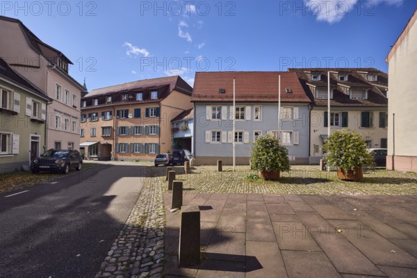 Houses, residential buildings, apartment buildings, façade with windows and shutters, dormers, church, flower pot, street, barrier bollard, curve, blue sky, cumulus clouds, Kirchstraße, Staufen im Breisgau, Black Forest, Breisgau-Hochschwarzwald district, Baden-Württemberg, Germany