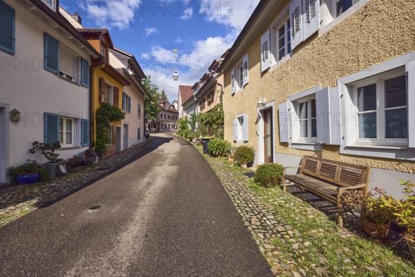 Residential buildings, apartment buildings, houses, general architecture, entrance, façade with windows and shutters, bench, flower pots, wet road, blue sky, cumulus clouds, alleyway St.-Johannesgasse, Staufen im Breisgau, Black Forest, Breisgau-Hochschwarzwald district, Baden-Württemberg, Germany