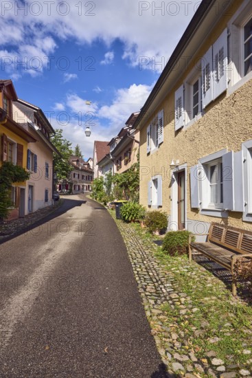 Residential buildings, apartment buildings, houses, general architecture, entrance, façade with windows and shutters, bench, flower pots, wet road, blue sky, cumulus clouds, alleyway St.-Johannesgasse, Staufen im Breisgau, Black Forest, Breisgau-Hochschwarzwald district, Baden-Württemberg, Germany