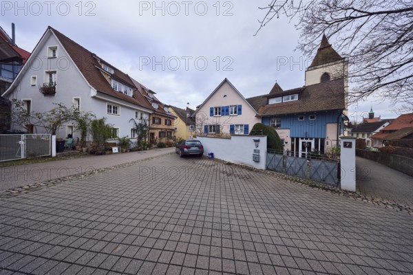 St. Martin church tower, general architecture, houses, residential buildings, apartment building, lantern, car, concrete paving road surface, cloudy, diffused light, St.-Johannesgasse, Staufen im Breisgau, Black Forest, Breisgau-Hochschwarzwald district, Baden-Württemberg, Germany