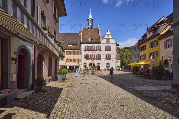 Historic town hall, market fountain, general architecture, historic buildings, houses, street, paving walkway, pedestrians as accessories, blue sky, cumulus clouds, intersection of main street with Kirchstraße, Staufen im Breisgau, Black Forest, Breisgau-Hochschwarzwald district, Baden-Württemberg, Germany