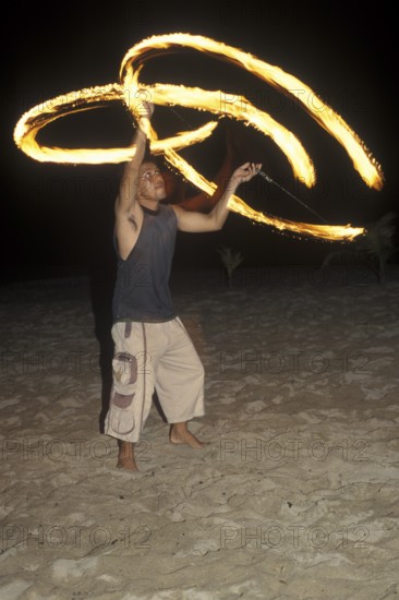 A man waves burning torches on the beach of Coral Beach Resort on the island of Ko Lanta, Thailand, December 2002, vintage, retro, old, historic
