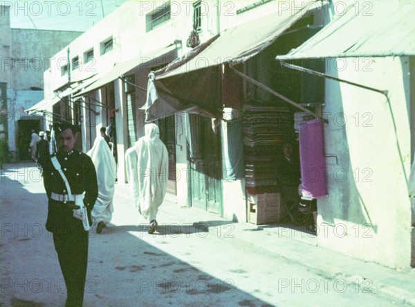 Policeman standing in street of small shops in souk of old town medina, Tripoli, Libya, North Africa 1956
