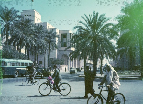 People cycling in city street, traffic in road passing Al Waddan Hotel, Sharia Sidi Issa, Tripoli, Libya, North Africa 1956