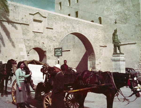 Horse and carriage taxi in city street next to Cabs Vetture sign and Roman statue of Emperor Septimius Severus, Tripoli, Libya, North Africa 1956
