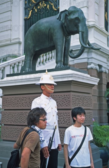 Tourists pose for photo in front of palace guard, Grand Palace at Wat Phra Kaeo, Bangkok, Thailand, December 2002, vintage, retro, historic