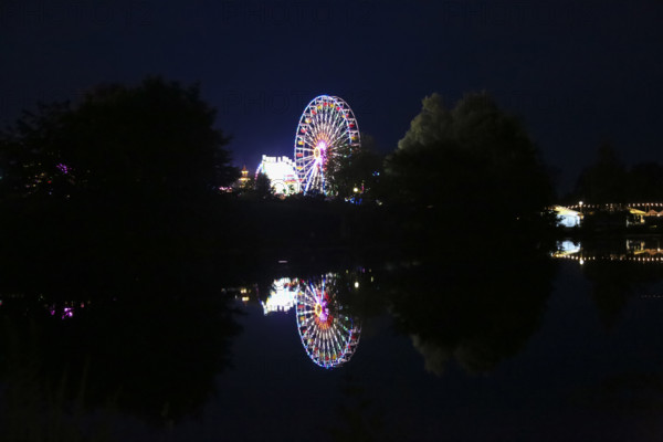 Fairground in Ulm Friedrichsau at night, folk festival, hustle and bustle, fair, Ferris wheel, amusement park, amusement attraction, ride, artificial light, darkness, reflection in natural lake, Ausee, Ferris wheel, Ulm, Baden-Württemberg, Germany