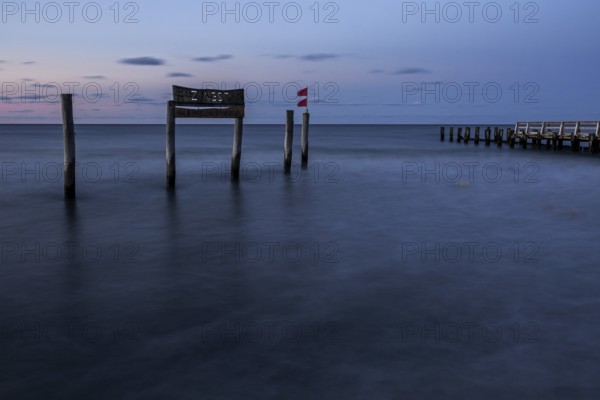 Wooden sign in the sea with inscription Zingst and wooden walkway, long exposure, evening light, Zingst, Fischland-Darß-Zingst, Western Pomerania National Park, Mecklenburg-Western Pomerania, Germany