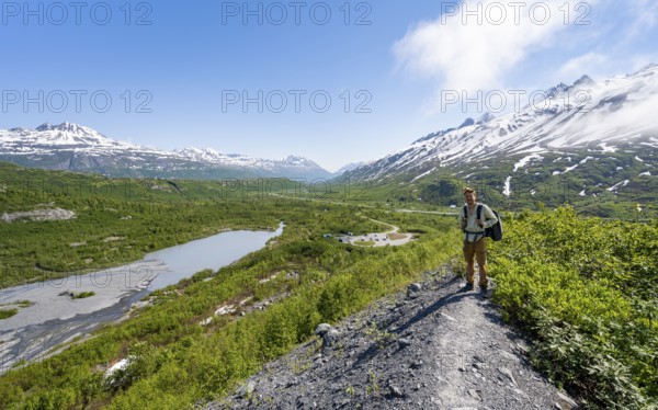 Hikers on glacial moraine, view of the vast Tsina River valley with mountains, Worthington Glacier Lagoon, Worthington Glacier State Recreational Site, Chugach Mountains, Alaska, USA