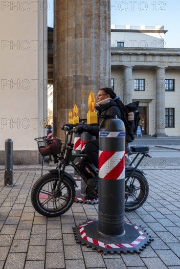 Passers-by at the security barrier made of massive bollards at the Brandenburg Gate passage, Berlin, Germany