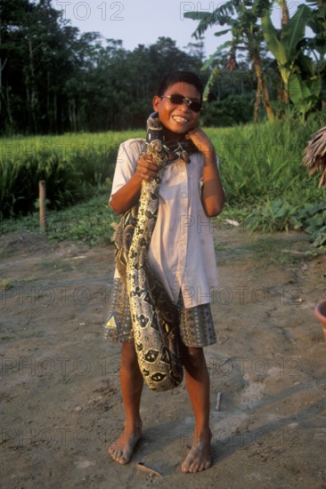 A boy whose father runs a small private zoo near Iquitos on the Amazon shows a boa, Peru, South America, September 1997, vintage, retro, old, historic