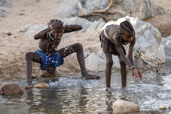 Himba child washing with water on a river, traditional Himba, Kaokoveld, Kunene, Namibia