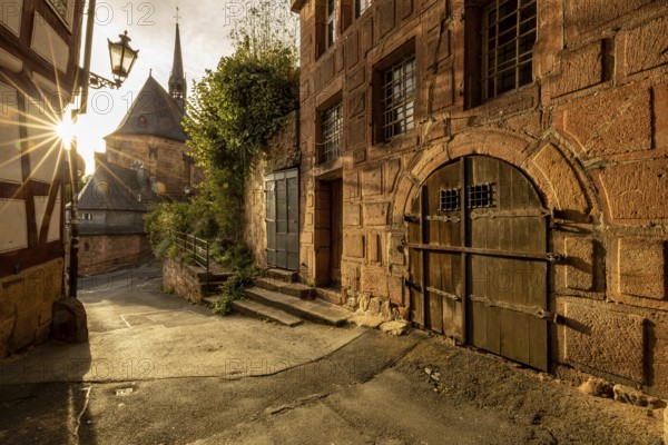 Historic alley with half-timbered houses and church in sunlight with a quiet atmosphere, The historic alleys and streets of the old town of Marburg