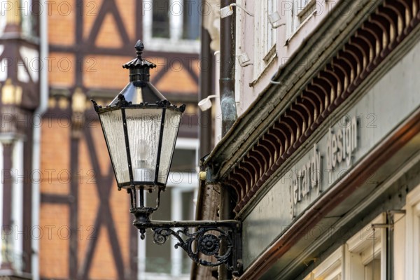 Nostalgic lantern next to a building in front of half-timbered buildings and windows in urban space, The historic street lamps of Marburg an der Lahn in Hesse