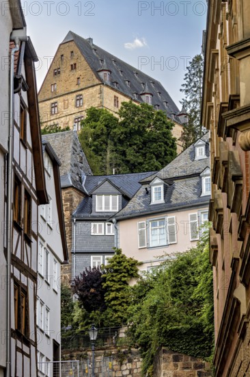 Enge Gasse in Marburg with historic half-timbered and stone buildings under a wooded hill, The Landgrave Castle of Marburg in Hesse