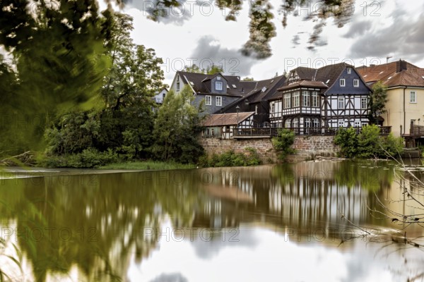 Half-timbered houses on the lake with dramatic clouds and reflections in the water, The historic houses of Marburg are reflected in the Lahn in Hesse