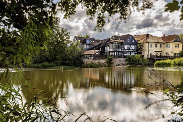 Half-timbered houses on the lake under cloudy skies, surrounded by nature, The historic houses of Marburg are reflected in the Lahn in Hesse