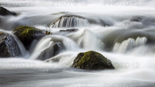Running water over moss-covered stones in a quiet, natural environment, the small river Lahn flows over stones