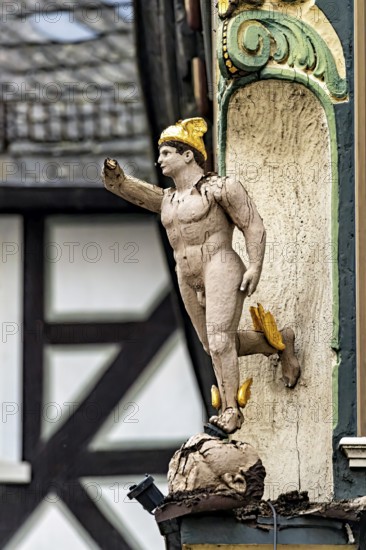 An ornate wooden statue in Roman style as building decoration, gilded details, historic and traditional atmosphere, historic wooden figure in the old town of Marburg an der Lahn in Hesse