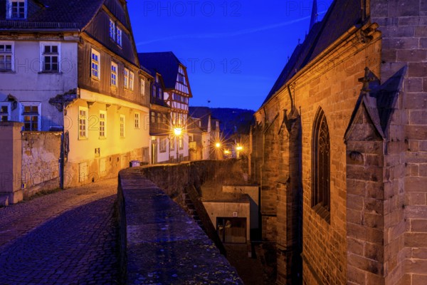 Historic street view at dusk with illuminated half-timbered houses and a church building, At the blue hour in Marburg city center in Hesse