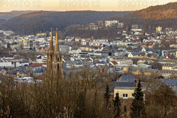 View of a town with a church and surrounding hills at sunset, view of the city of Marburg with the Elisabeth church