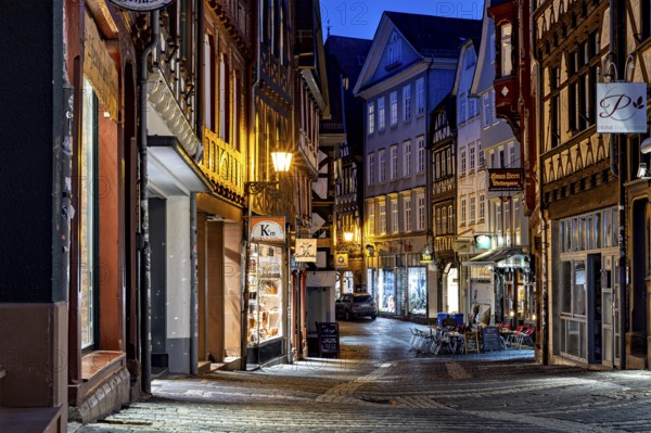 Narrow old town alleyway at night with illuminated shops and historic half-timbered buildings, At the blue hour in Marburg city center in Hesse