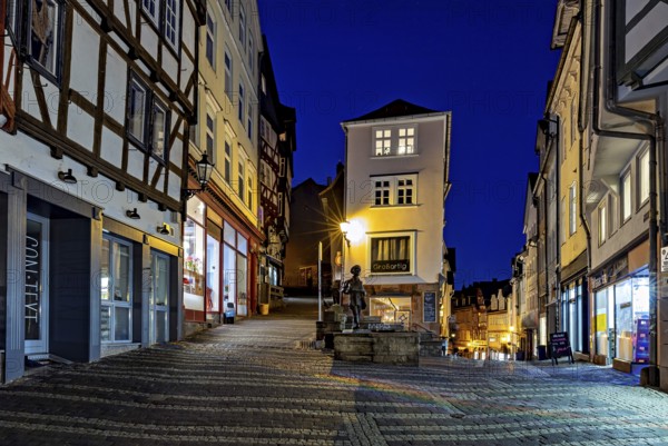 Night view of an old town street with illuminated facades and cobblestones, At the blue hour in the city center of Marburg in Hesse
