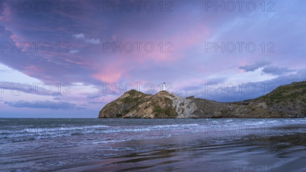 Castlepoint Beach, ocean and lighthouse on a rock, evening, sunset, dramatic sky. Castlepoint, Wairarapa Coast, Wellington Region, North Island, New Zealand