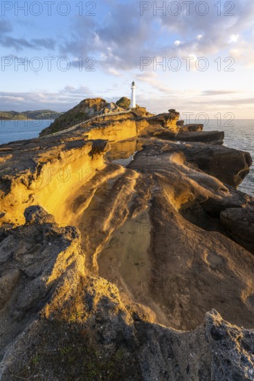 Castlepoint lighthouse on a rock, sea, sunrise. Castlepoint, Wairarapa Coast, Wellington Region, North Island, New Zealand