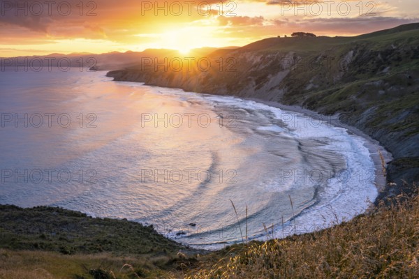 Wairarapa coast at sunset. Sea, mountains, backlight. Castlepoint, Wairarapa Coast, Wellington Region, North Island, New Zealand