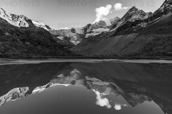 The Moiry glacier and mountain peaks are reflected in Lac de Chateaupre, black and white photo, Val d'Anniviers, Valais Alps, Canton of Valais, Switzerland