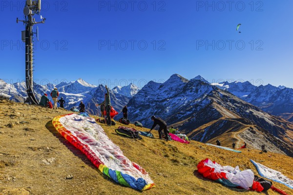 Paragliders are preparing for their start, with the snow-capped peaks of the Valais Alps, Val d'Anniviers, Canton of Valais, Switzerland