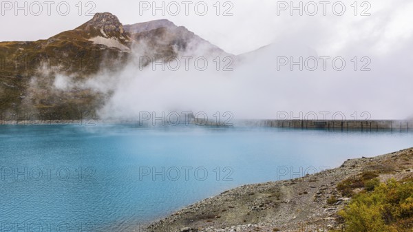 Fog rises over the dam of the Lac de Moiry Reservoir, Val d'Anniviers, Valais Alps, Canton of Valais, Switzerland