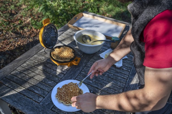 Preparation of waffles with a waffle iron on an outdoor garden table, Othenstorf, Mecklenburg-Western Pomerania, Germany