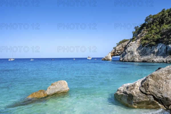 Light blue clear sea on a dream beach on Cala Goloritzé, picturesque rocky coast, cliffs with rock arch, Golfo di Orosei, Baunei, Sardinia, Italy