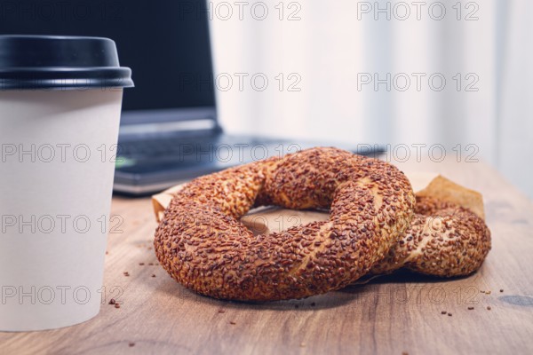 Simits with coffee on a wooden table, with a laptop, in a cozy working environment, snack, breakfast, no people