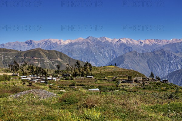 A small village in a mountainous landscape under blue skies with extensive views of the surrounding mountains and nature, the landscape with village at Colca Canyon in the Andes in Peru