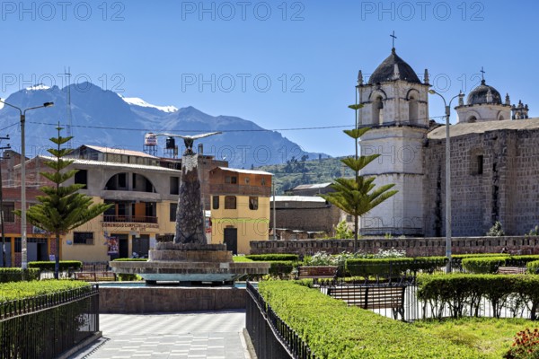 A square with a church against a mountain backdrop in sunny weather and clear skies, the town of Colca in Peru