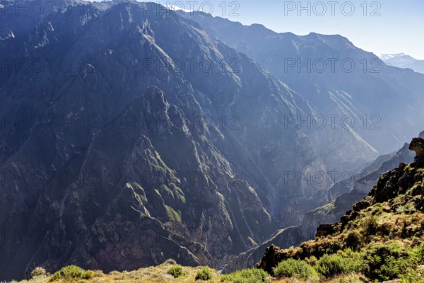 Deep canyon surrounded by high mountains in sunlight with shady areas, the mountains and valleys of the Colca Canyon in Peru