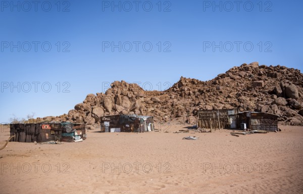 Simple poor huts made of corrugated iron and wood, desert landscape, barren landscape with hills of stacked rocks, Brandberg, Erongo, Damaraland, Namibia