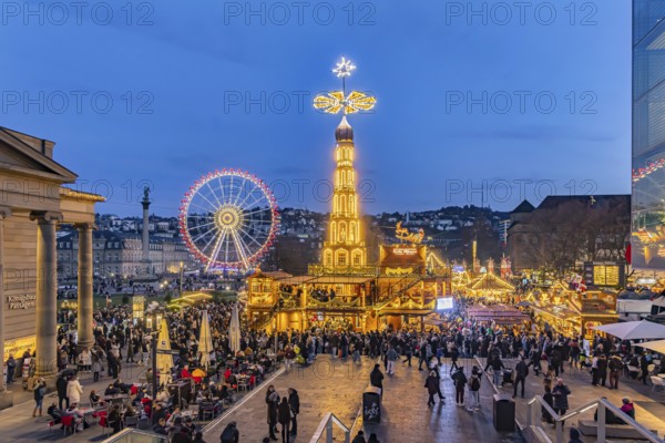 Evening atmosphere at Stuttgart's Christmas market in the Schlossplatz area. With around 3.5 million visitors, it is one of the largest and most beautiful in all of Germany. Christmas pyramid and Ferris wheel in front of the New Castle. Stuttgart, Baden-Württemberg, Germany