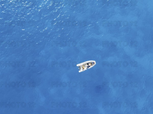 Young woman and young man lying in a motor boat on a blue sea, top-down, aerial view, Golfo di Orosei, Baunei, Sardinia, Italy