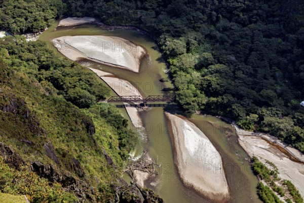 Aerial view of a river with sandbanks and a bridge surrounded by thick forest, view of the Urubamba Valley near Machu Picchu in Peru