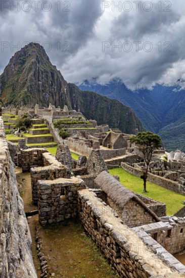 View of the ruined city of Machu Picchu with surrounding Andes and cloudy sky, The ruins of the Inca city of Machu Picchu in Peru