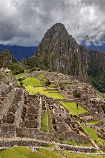 Aerial view of Machu Picchu ruins and mountainous landscape under cloudy sky, The ruins of the Inca city of Machu Picchu in Peru