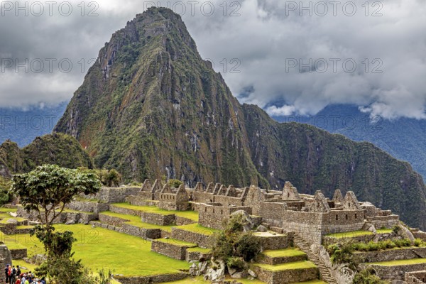 Majestic mountain behind ancient ruins under thick grass and clouds, The ruins of the Inca city of Machu Picchu in Peru