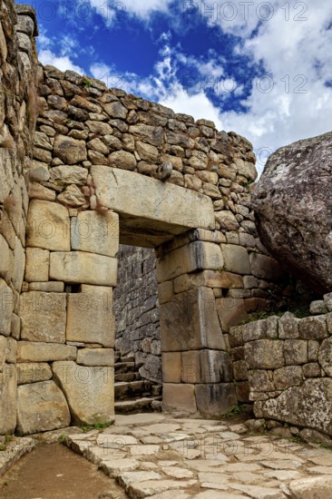 Inca stone archway with blue sky and some clouds, The ruins of the Inca city of Machu Picchu in Peru